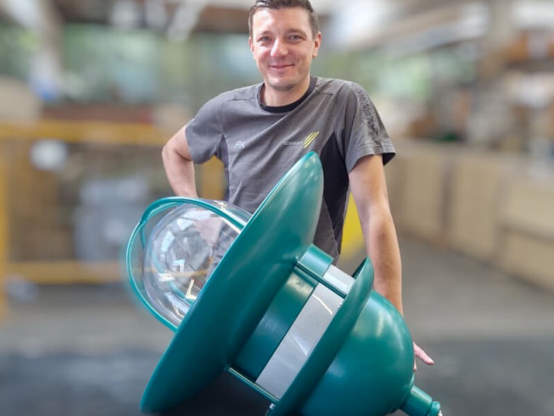 der Mitarbeiter Peter Kremer steht hinter einer umgerüsteten grünen Stadthausleuchte