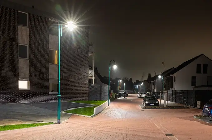 Wohnstraße in Duisburg bei Nacht mit modernen Straßenleuchten, die Gehweg und Fahrbahn gleichmäßig ausleuchten, umgeben von Wohnhäusern und parkenden Autos